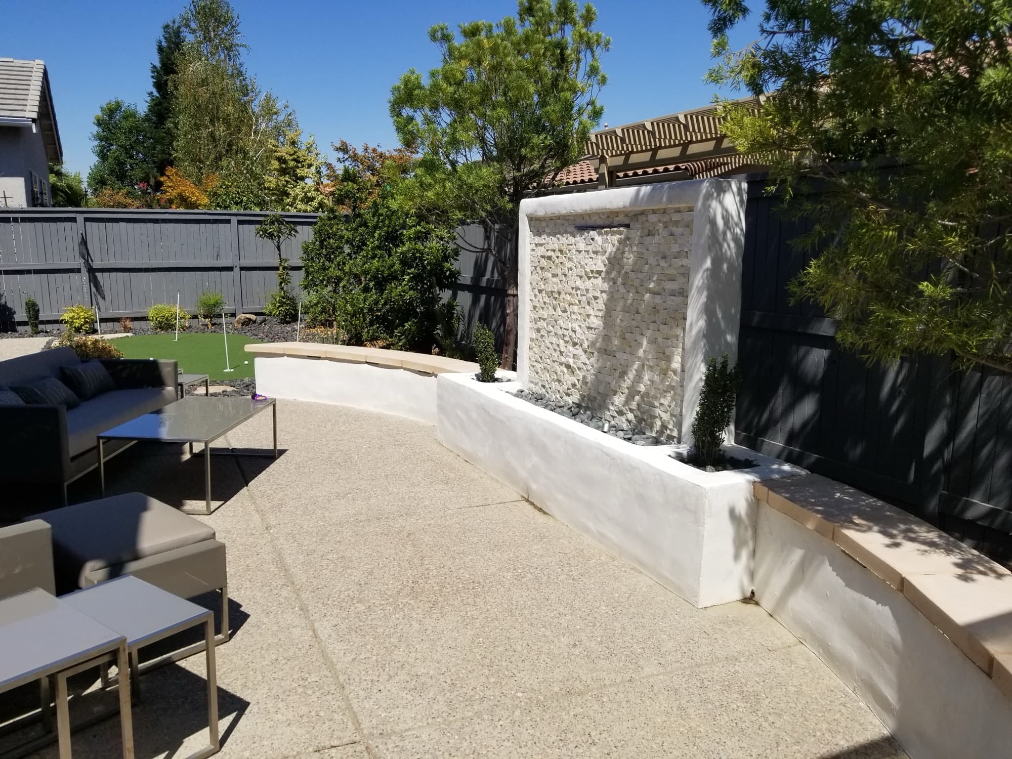 Stacked-stone water feature wall overlooking a backyard putting green built by Holt Landscape in Loomis, CA