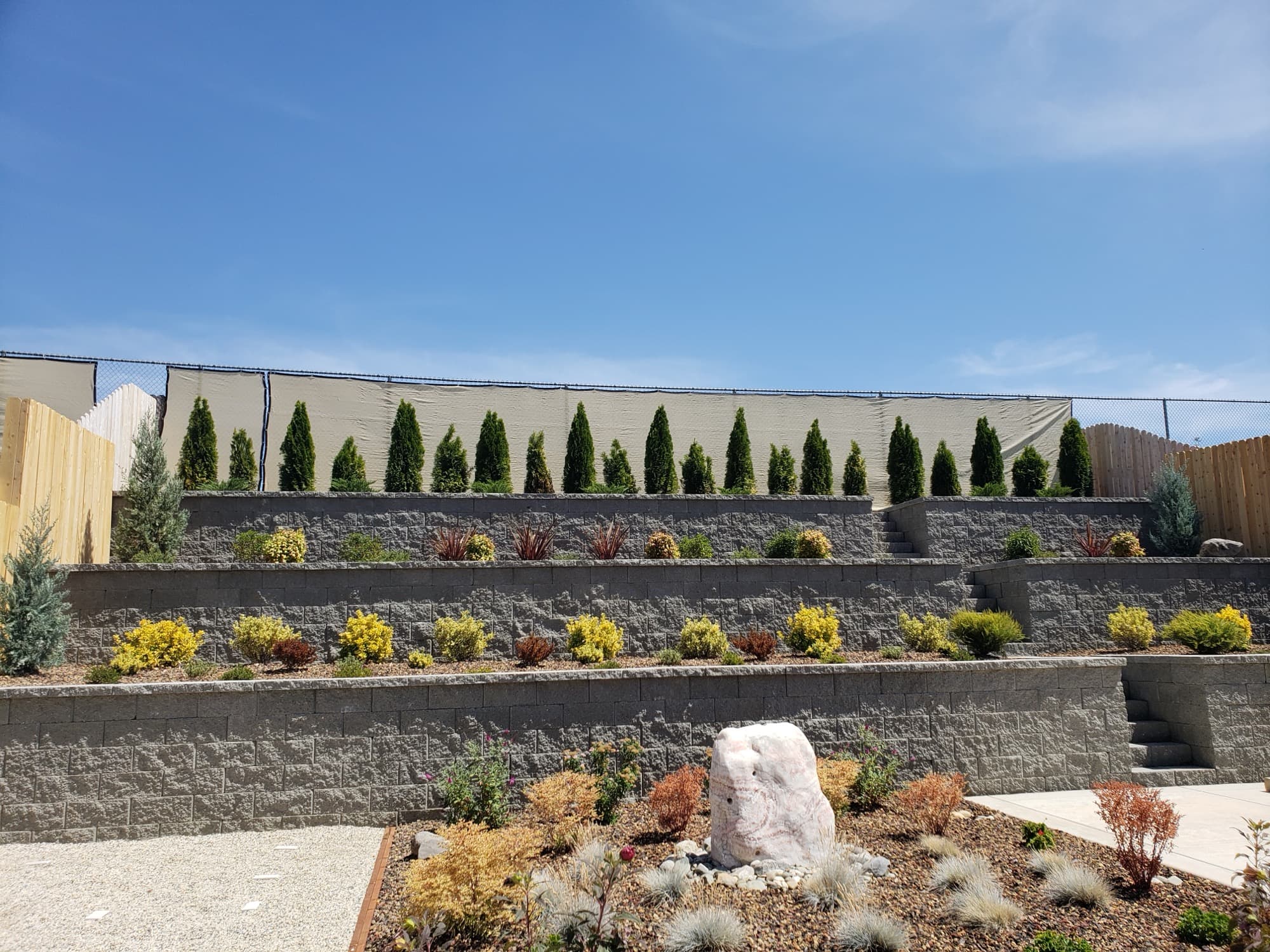 Tiered stone retaining walls with layered shrub plantings installed by Holt Landscape near Lincoln, CA