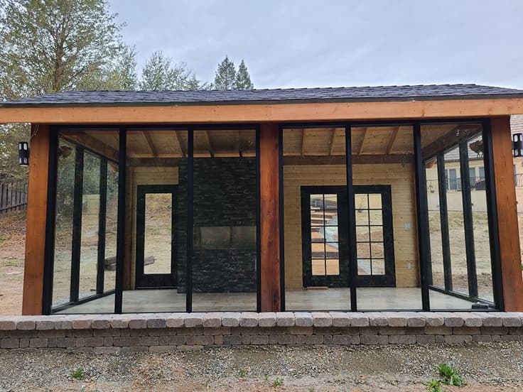 Glass-enclosed cabana with a cedar timber-frame roof built by Holt Landscape in Roseville, CA