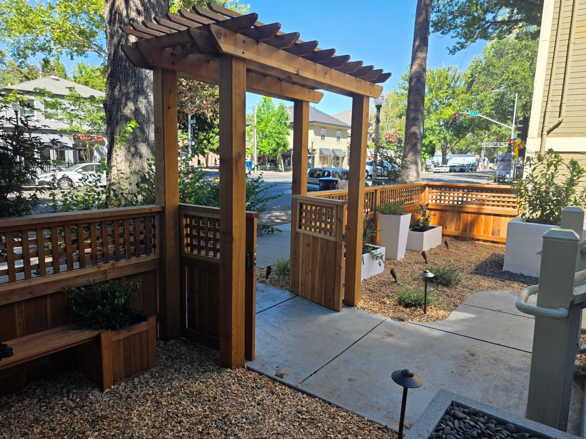 Cedar entry arbor with lattice fencing and landscape lighting installed by Holt Landscape near Folsom, CA